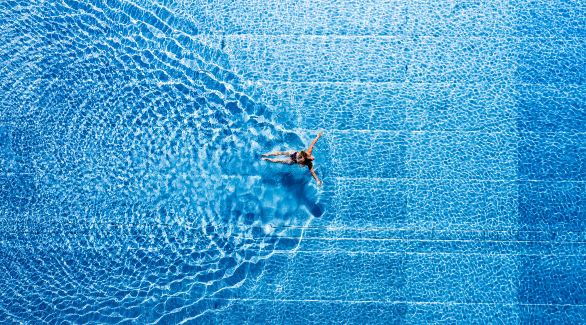 Vogelperspektive: eine Frau schwimmt in einem Swimmingpool im Freibad